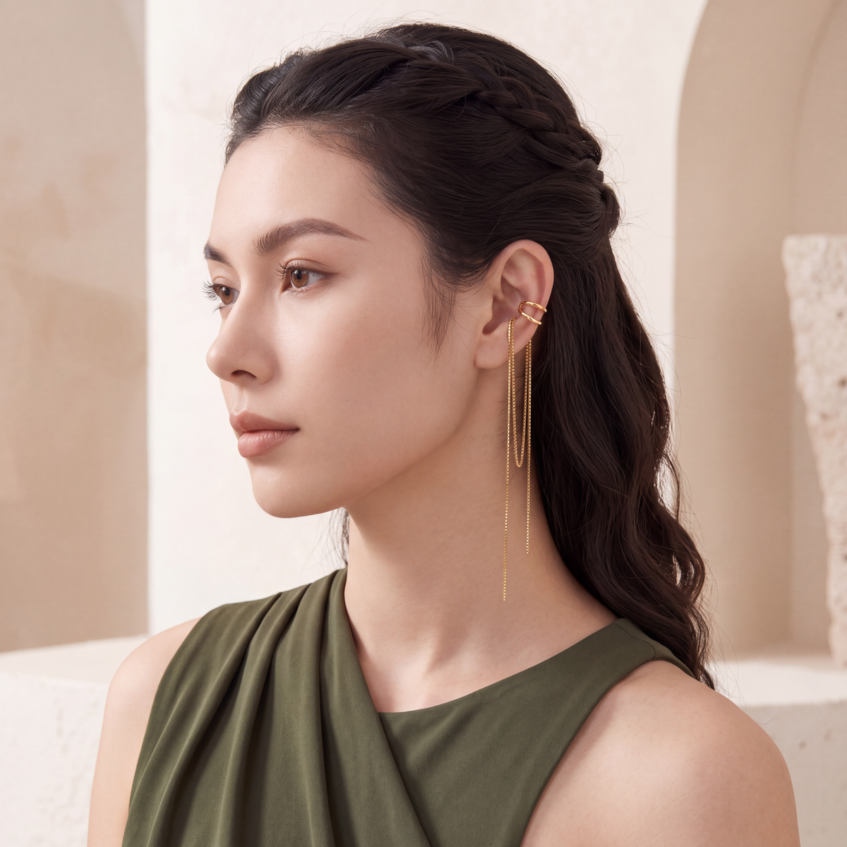 Golden Rain gold plated chain tassel ear cuff worn on the upper ear of a model with braided dark hair and an olive dress
