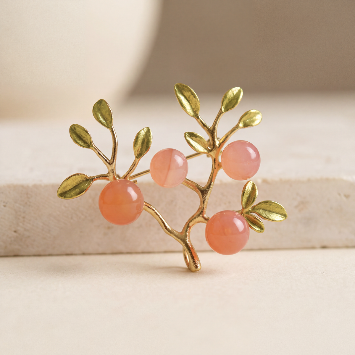 Peach Orchard Branch Brooch standing upright, gold plated branch with green enamel leaves and four natural red agate beads in peach tones
