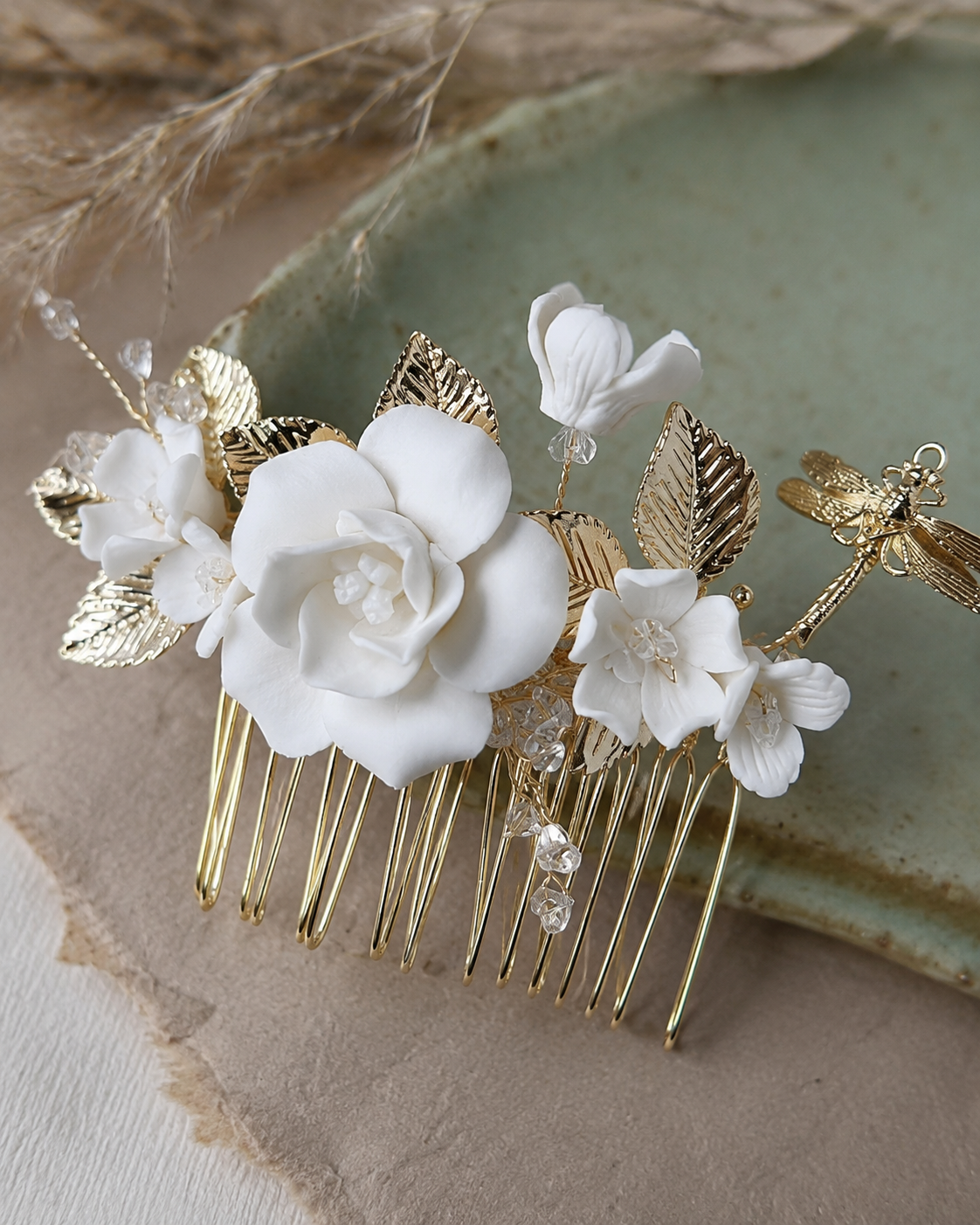 Gold bridal hair comb with white ceramic flowers and a dragonfly detail