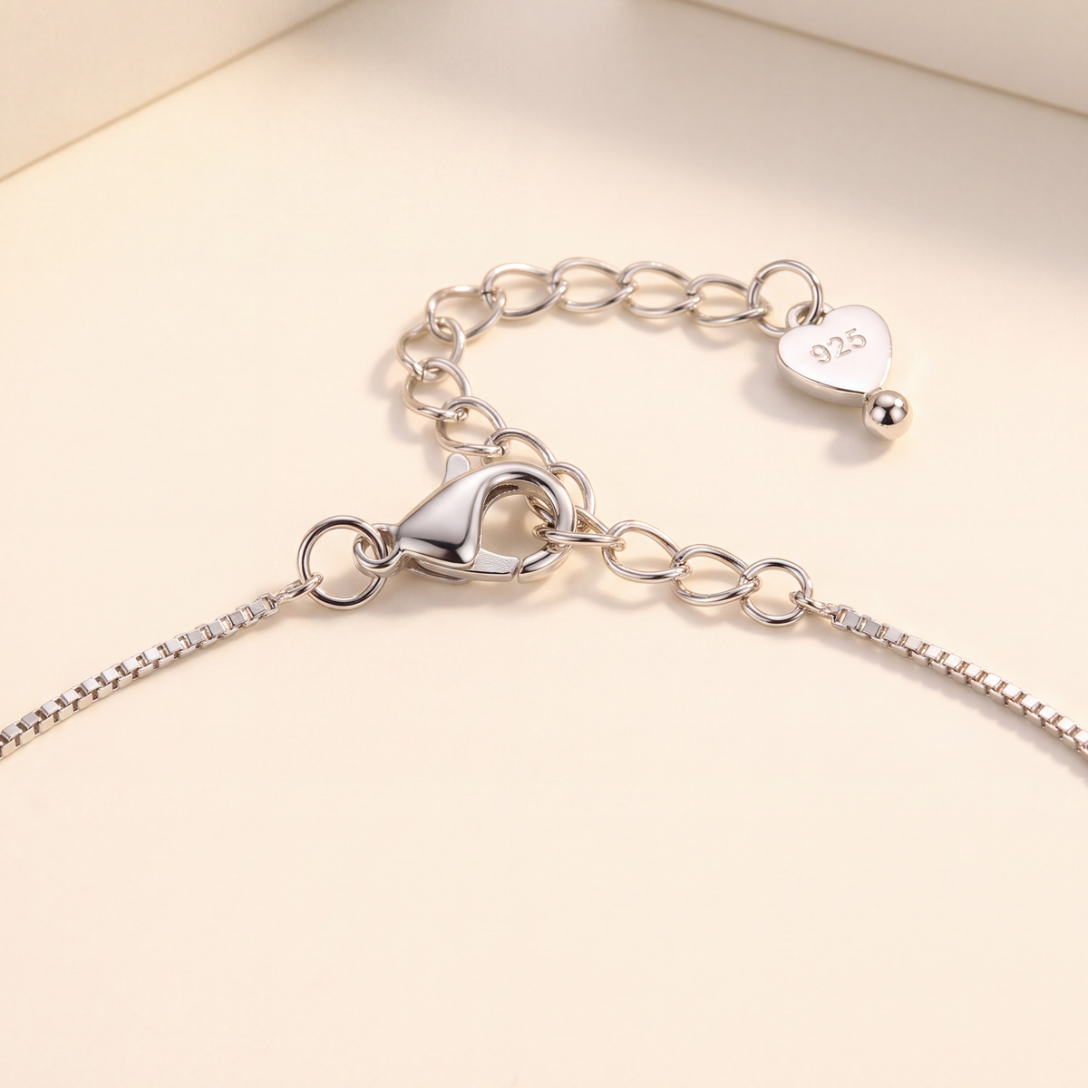 Juliet layered sterling silver necklace draped to show the moissanite heart halo pendant, beaded chain and lobster clasp