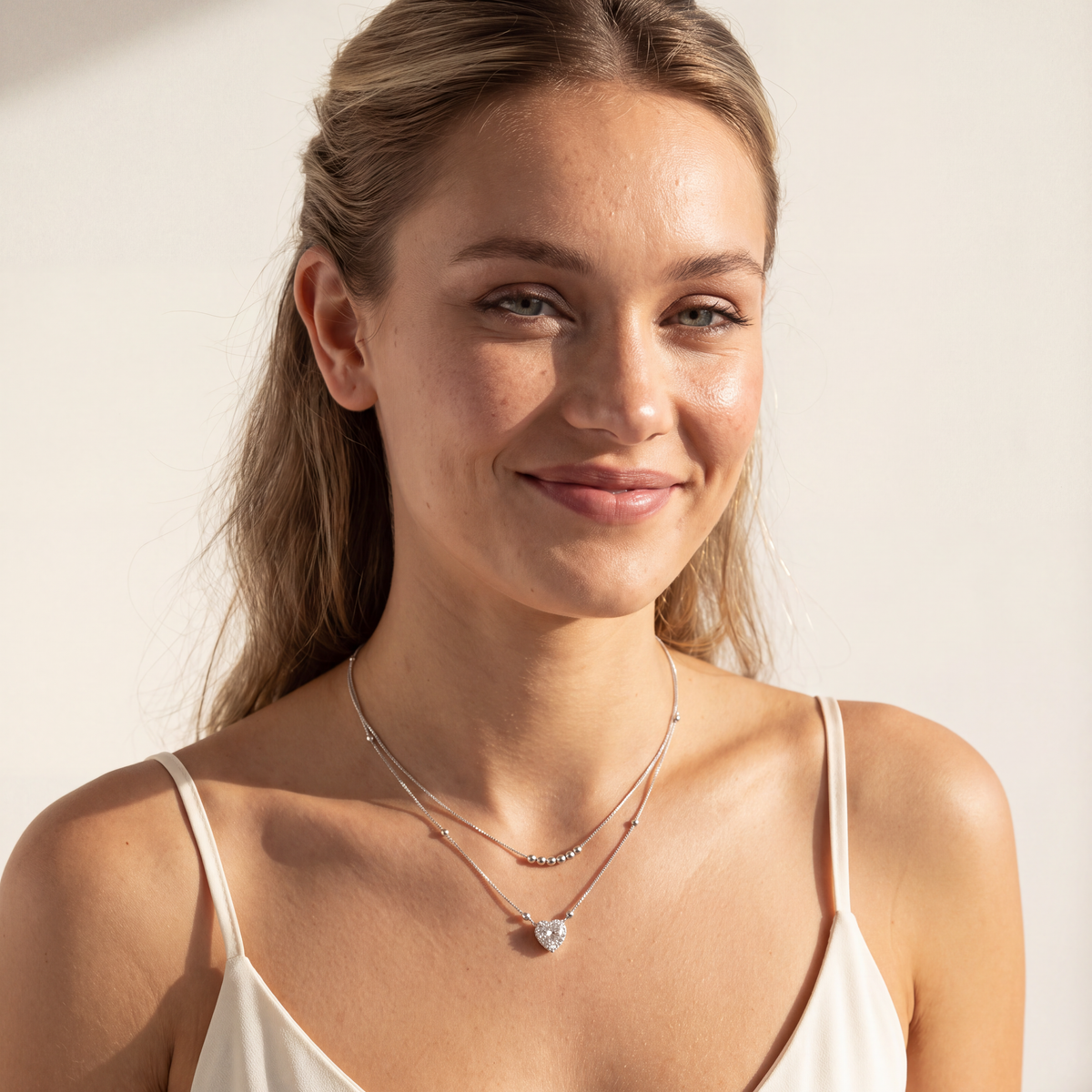 Model smiling and wearing the Juliet layered sterling silver necklace with 1 carat moissanite heart