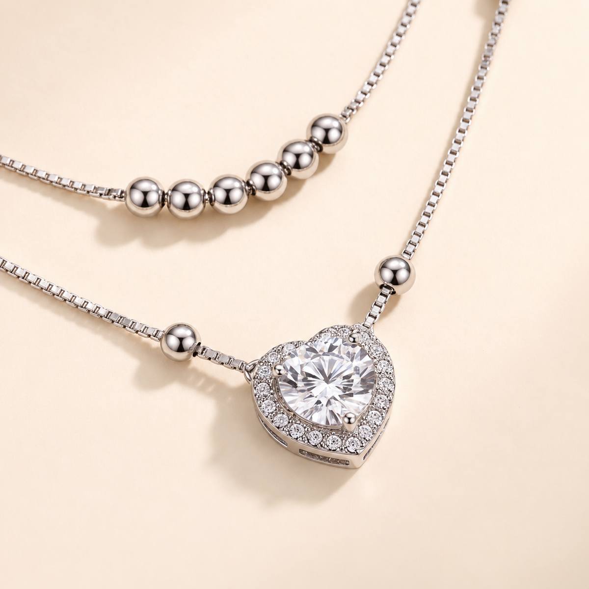Angled close up of the 1 carat moissanite heart pendant with halo and silver beads on the Juliet layered necklace
